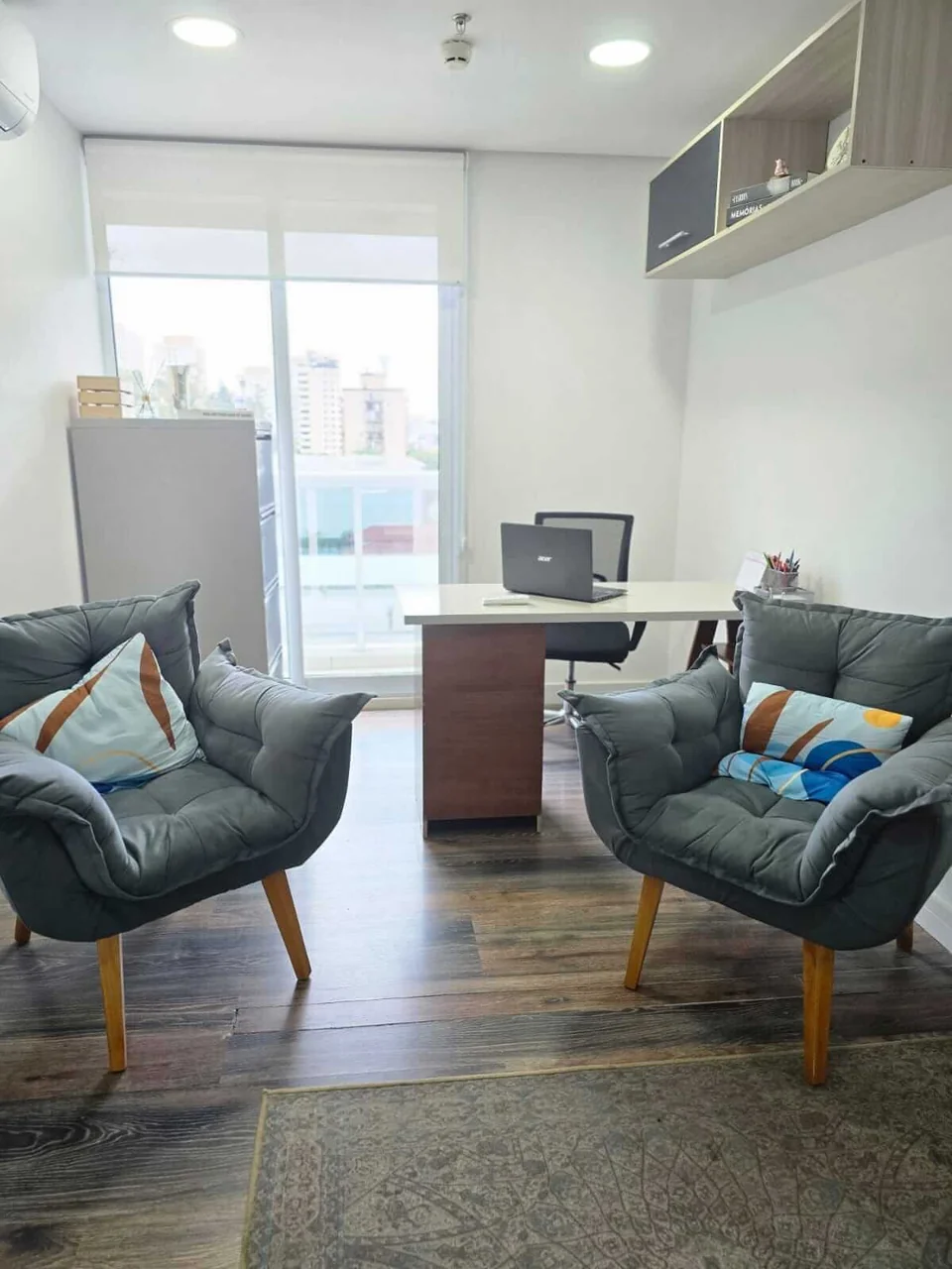 Sala de atendimento com duas poltronas e mesa de trabalho